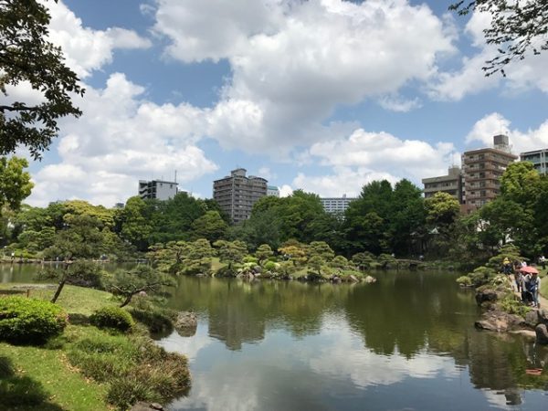 Metropolitan Gardens : 東京都故園, Japanese Culture, Kiyosumi garden lake reflecting the surrounding sky islet, trees, and modern buildings.