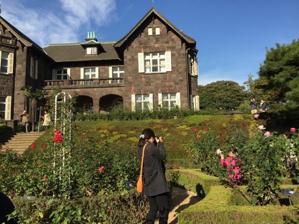 Metropolitan Gardens : 東京都故園, Japanese Culture, Woman taking a picture of her daughter at the rose garden in front of the brick mansion at Kyu-Furukawa gardens in Tokyo.