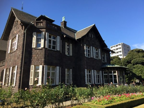 Metropolitan Gardens : 東京都故園, Japanese Culture, Two story, grey brick mansion behind a small rose garden.
