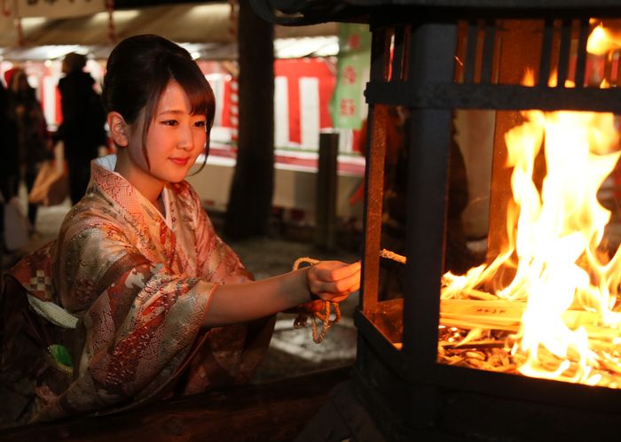 Okeramairi, Japanese Culture, A young woman lighting a rope to take home for good luck on New Year’s Eve in Kyoto., December in Japan