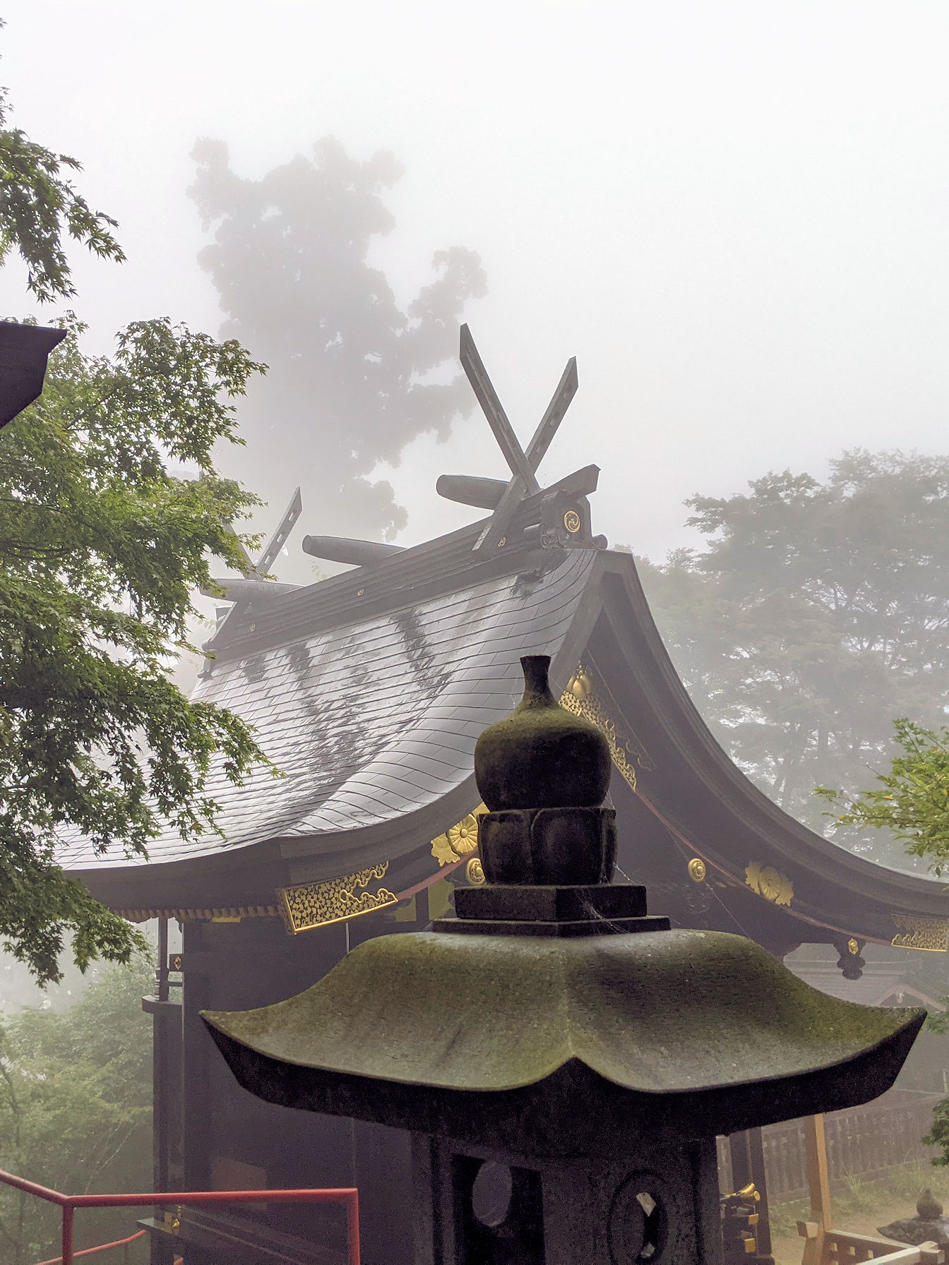 Image of a statue of a samurai riding a horse surounded by trees and old stone buildings. 